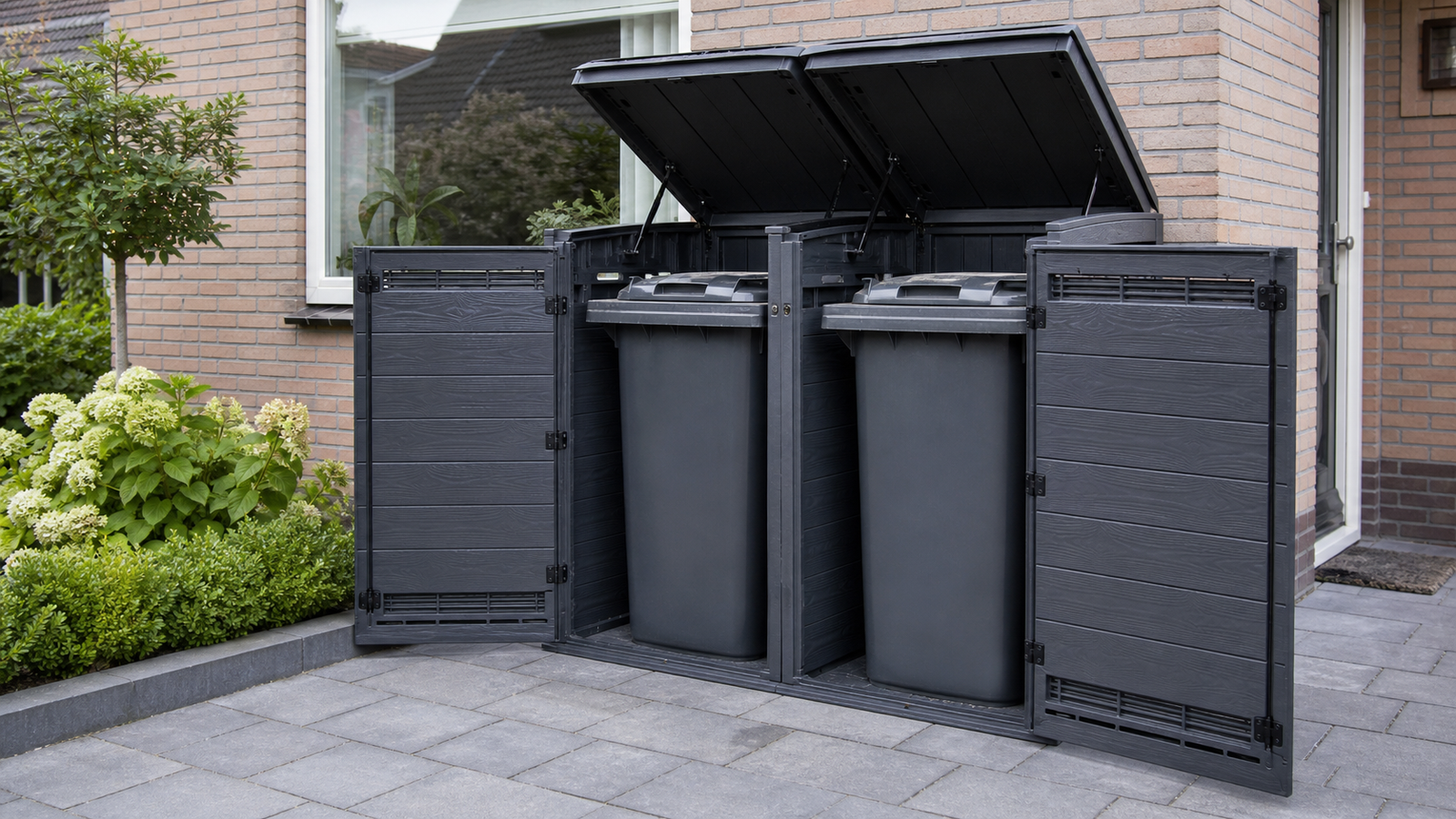 Antraciet kunststof containerombouw voor twee kliko’s op bestrating in een Nederlandse voortuin